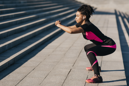 African American woman doing squats in an urban outdoor setting